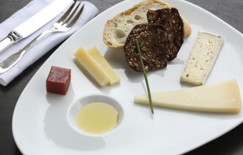 close up of a cheese plate with three cheeses, olive oil, and quince paste