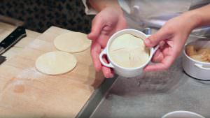 hands holding mini apple pie with dough on top