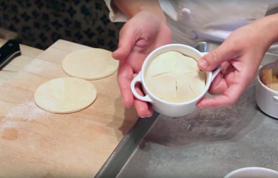 hands holding mini apple pie with dough on top