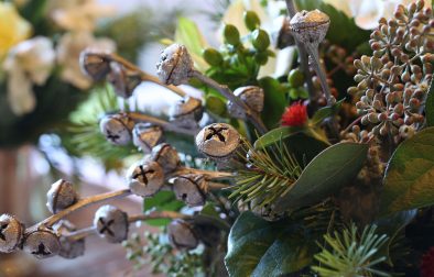 A close-up of eucalyptus pods painted silver to look like jingle bells in a holiday centerpiece.