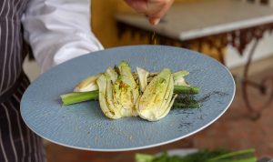 chef sprinkling fennel pollen onto grilled fennel