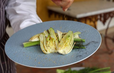 chef sprinkling fennel pollen onto grilled fennel