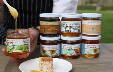 hands holding an open jar of honey next to other jars of honey