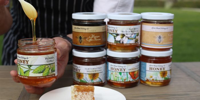 hands holding an open jar of honey next to other jars of honey