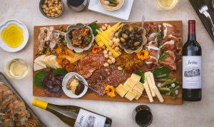 large charcuterie and cheese board with olives, pickles and marcona almonds and Jordan Winery Cabernet and Chardonnay