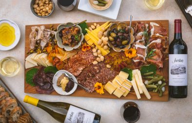 large charcuterie and cheese board with olives, pickles and marcona almonds and Jordan Winery Cabernet and Chardonnay