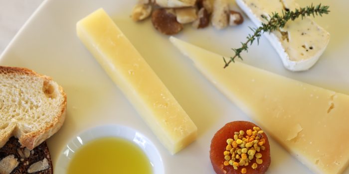 close up of cheese plate with quince paste topped with bee pollen and extra virgin olive oil