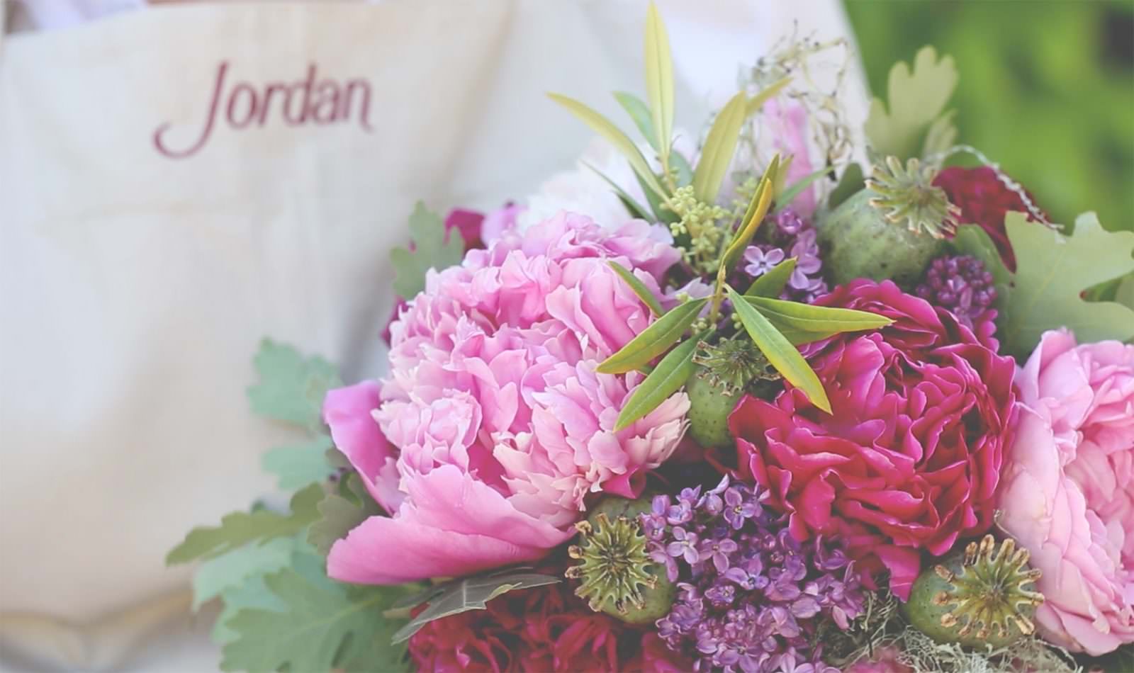 close up of a floral arrangement with peonies, roses and poppy pods
