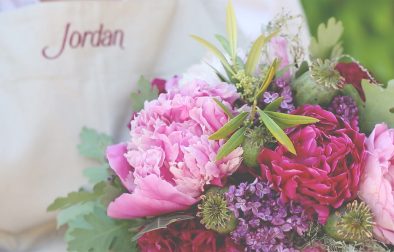 close up of a floral arrangement with peonies, roses and poppy pods