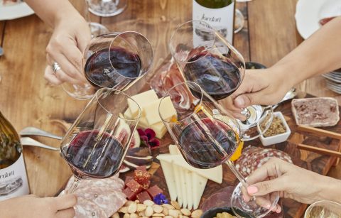 hands toasting with glasses of Jordan Winery Cabernet with charcuterie and cheese plate in background