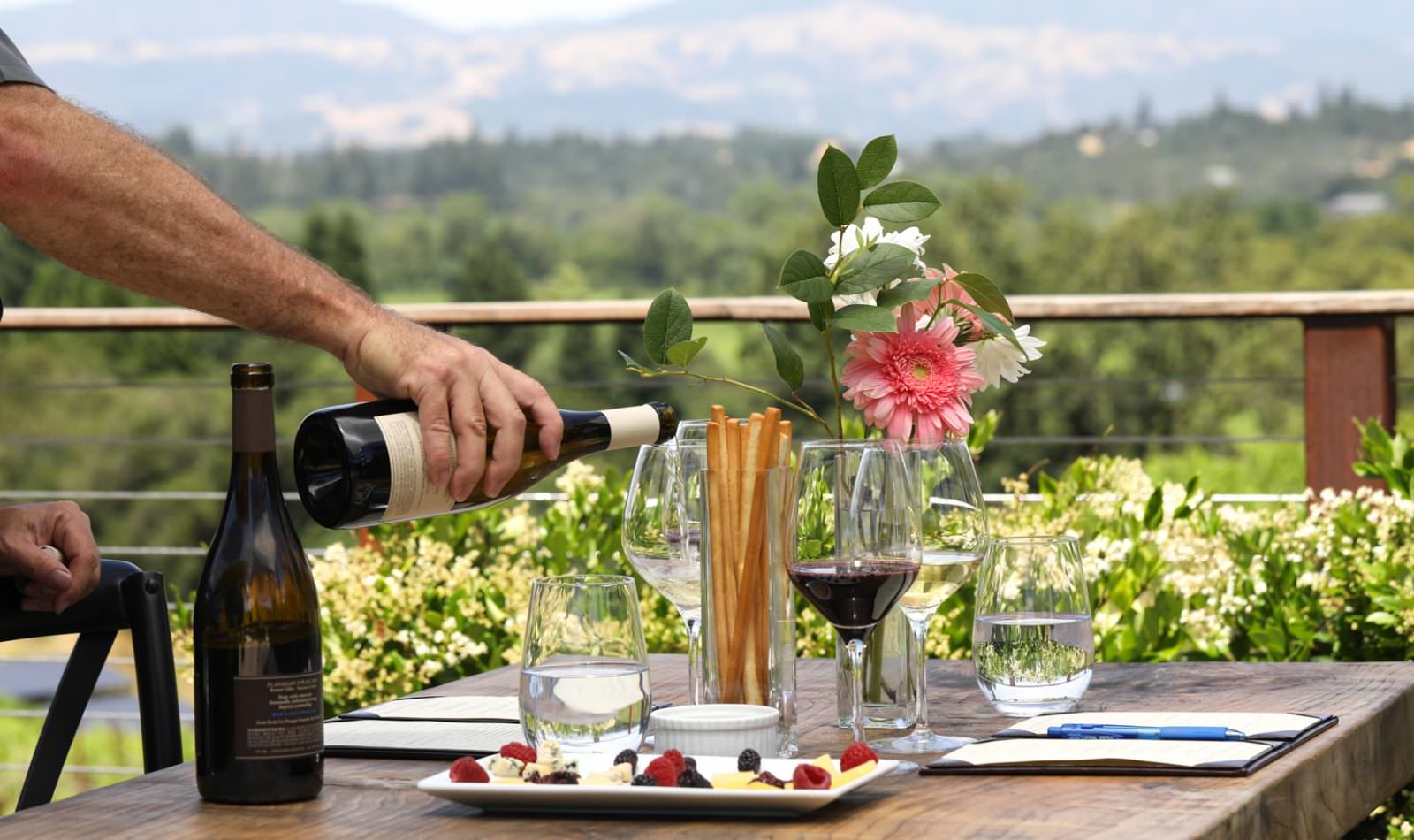 hands pouring wine at a table setting at Flanagan Winery's Cheese Pairing Wine Tasting