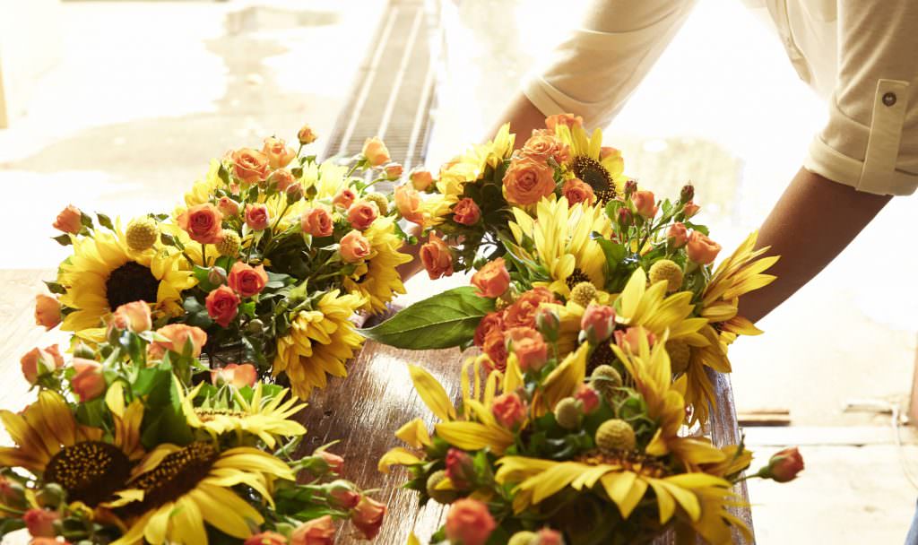 Floral centerpieces with sunflowers and orange spray roses