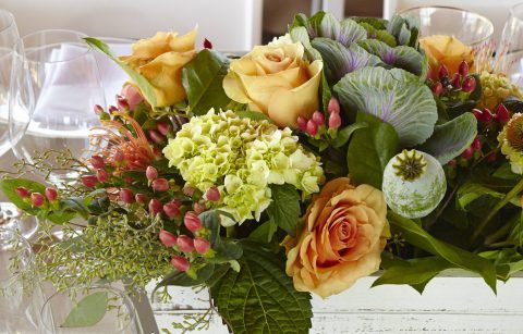 A floral arrangement with ornamental cabbage, smooth hydrangea, orange spray roses and orange flame calla lily.