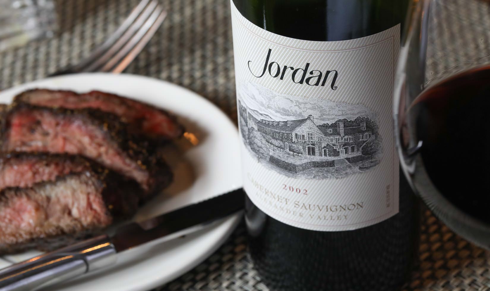 Sliced flat-iron steak on a plate awaits pairing with an older cabernet, like 2002 Jordan Cabernet Sauvignon.