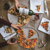 overhead shot of two people sitting at a table with pizza and Jordan winery Cabernet being poured into a glass