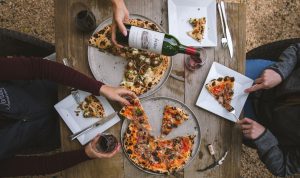 overhead shot of two people sitting at a table with pizza and Jordan winery Cabernet being poured into a glass