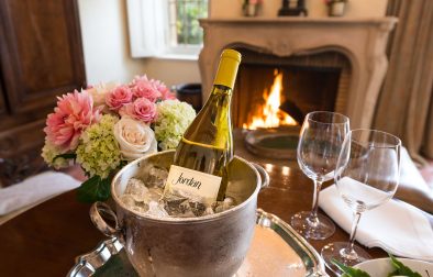 bottle of Jordan Chardonnay on ice next to wine glasses with fire burning in fireplace in background in a Jordan Winery suite