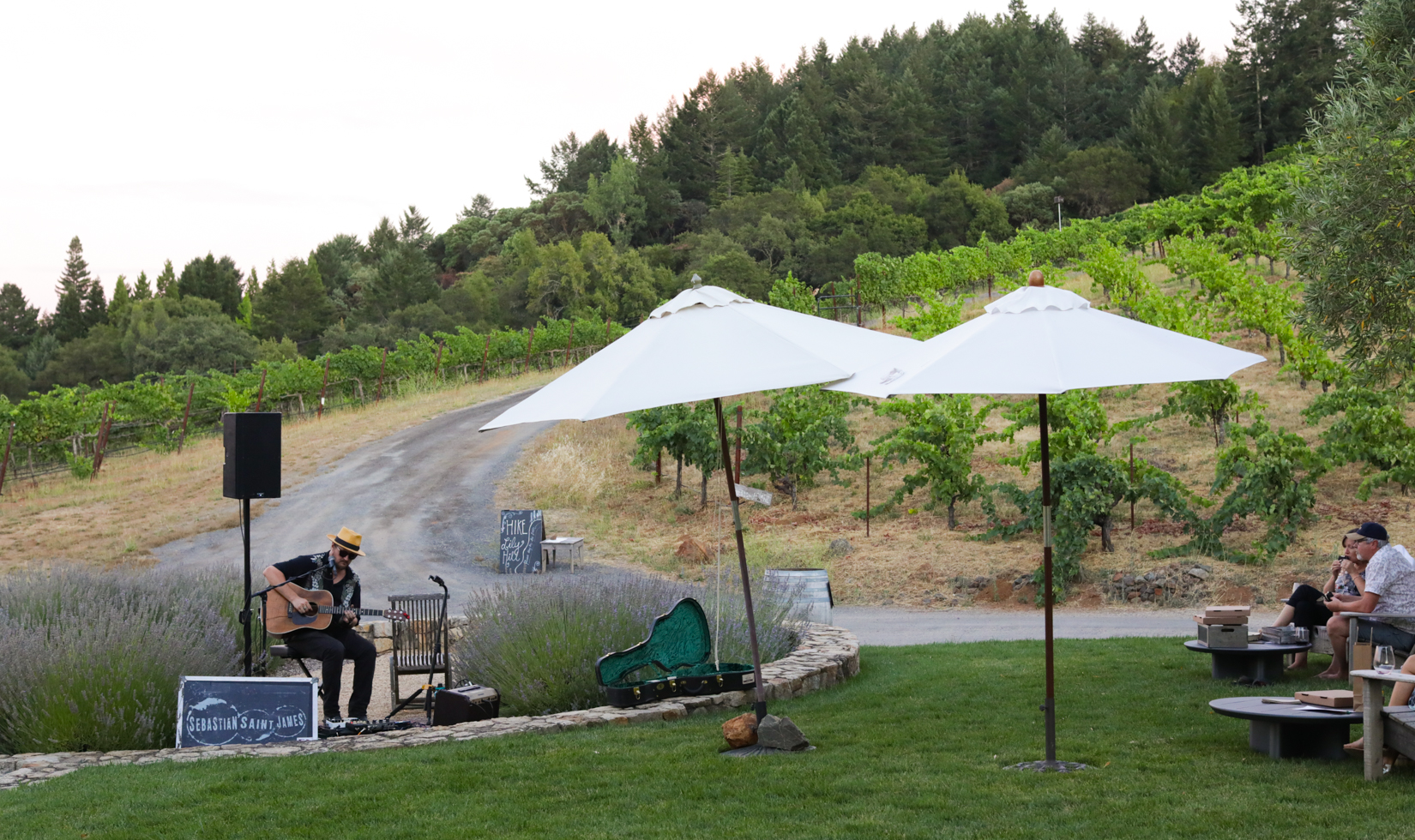 a man playing his guitar with speaker outdoor with 2 people listening