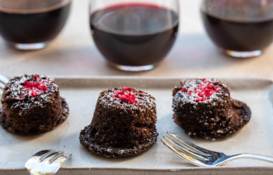 three Jordan Winery red wine chocolate cakes on a plate with red wine in glasses in the background