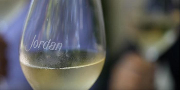 close up of a Jordan Winery etched wine glass with chilled Chardonnay in ti