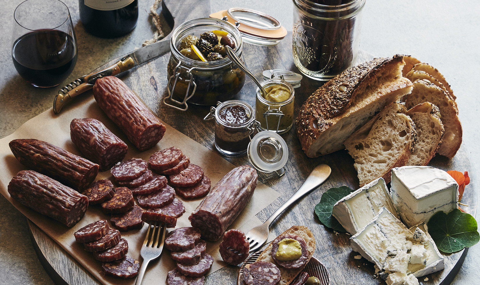 Journeyman salami on a cutting board with cheese and olives