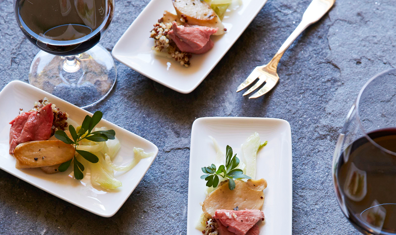 lamb with quinoa and mushrooms on small plates with wine glasses