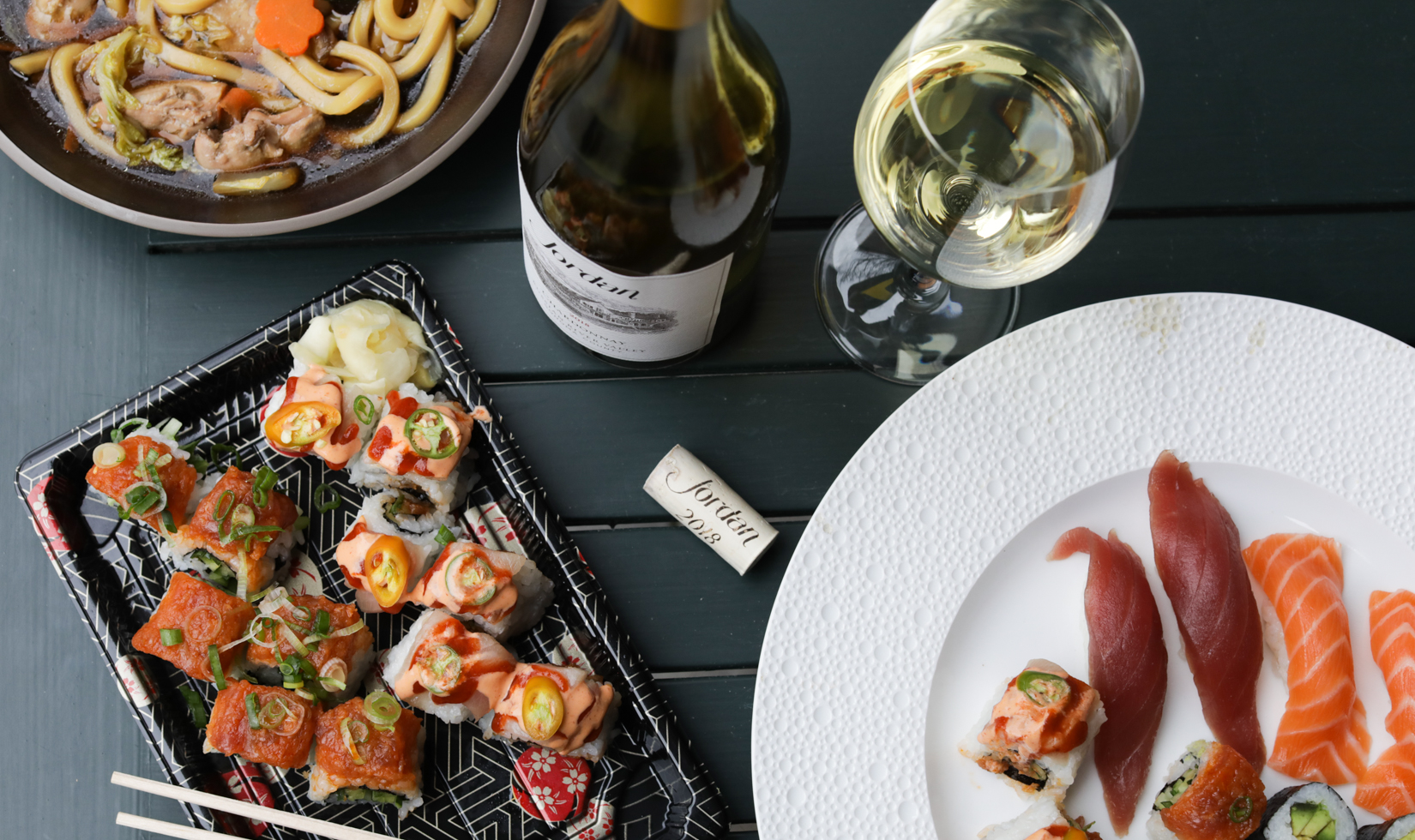 sushi rolls on plates with bottle of Jordan chardonnay and wine glasses