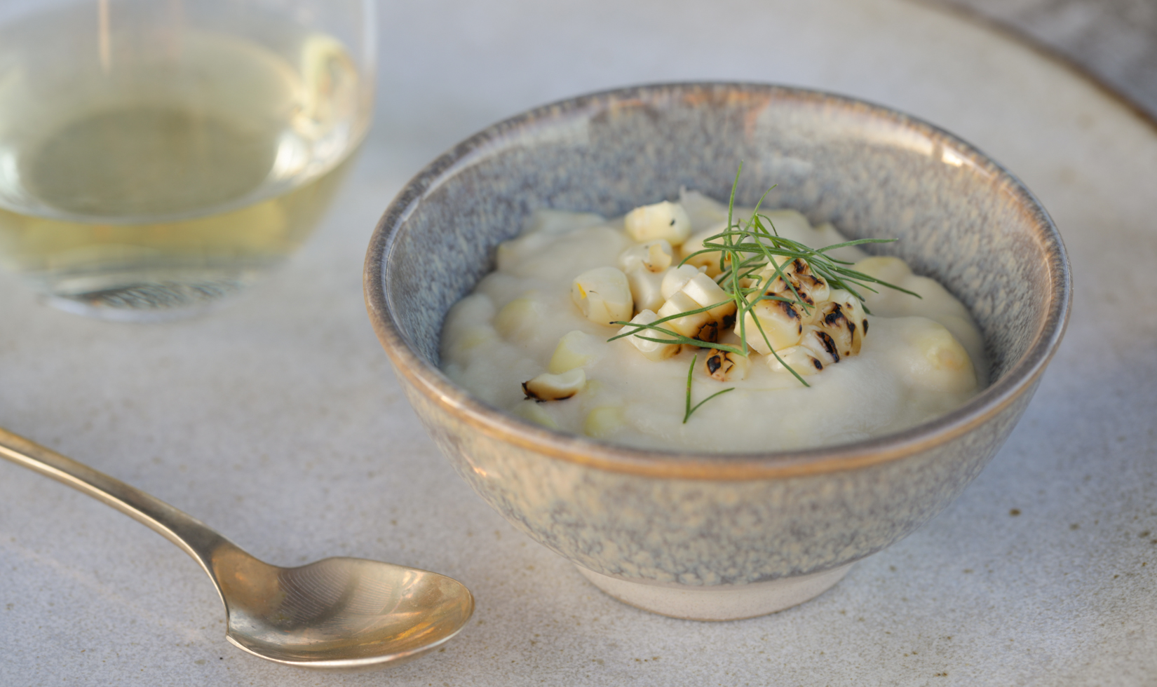 close up corn pudding in a grey bowl with spoon and jordan chardonnay wine