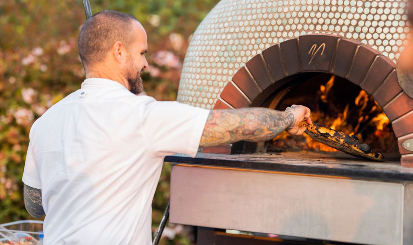 Outdoor Wine Tastings chef cooking pizza in a wood-fired oven