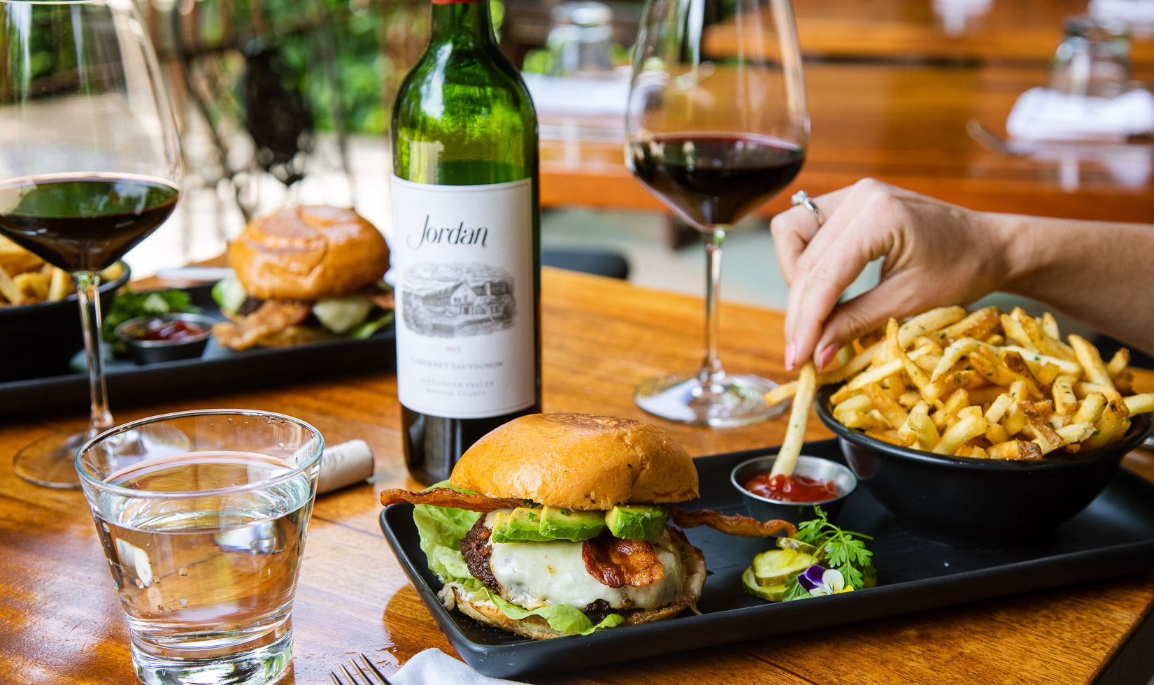 cheeseburger with side of french fries and bottle of Jordan Cabernet Sauvignon