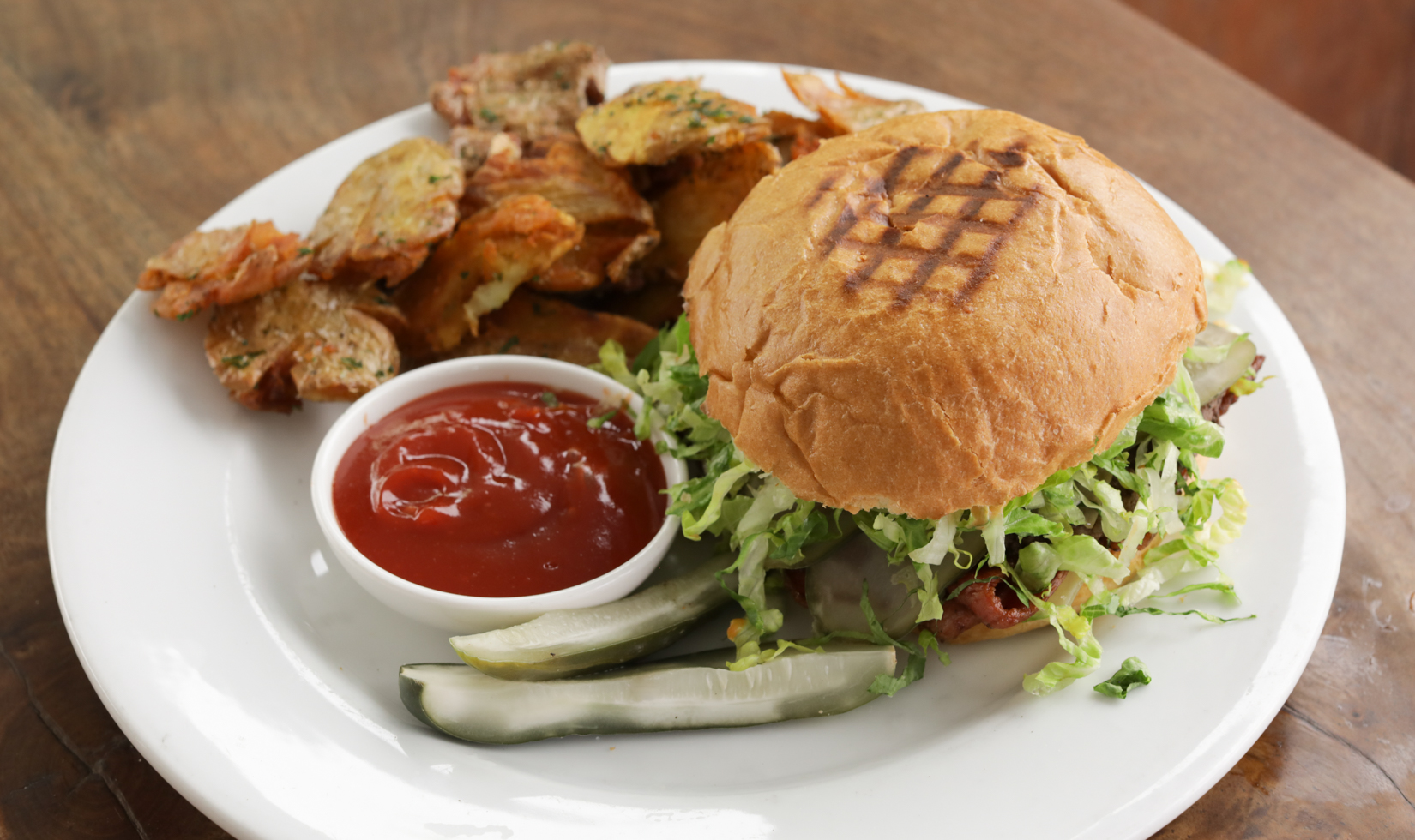 overhead of cheeseburger with pickle and potatoes