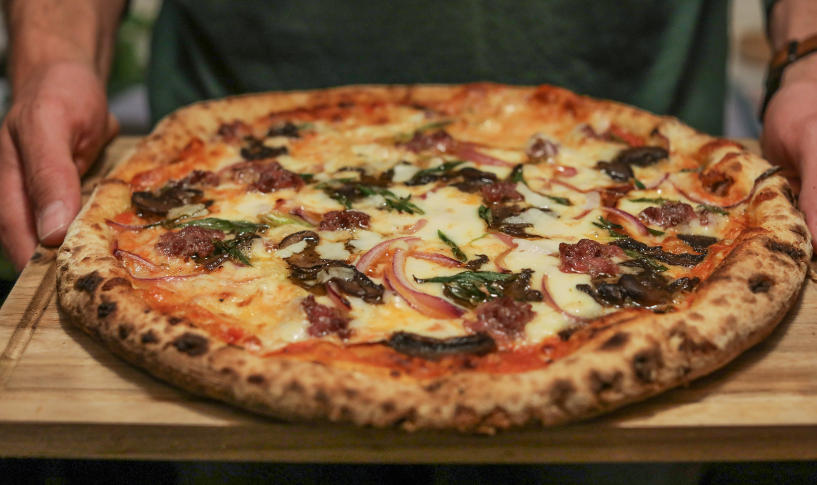 frozen sausage pizza on a wooden cutting board