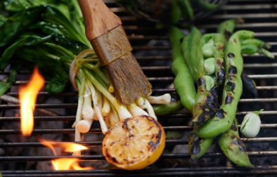 Green vegetables on a grill being brushed with oil