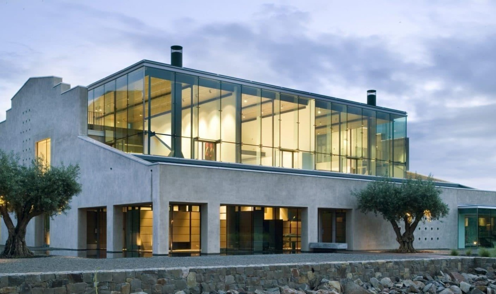 Modern concentrate restaurant building with large glass windows wrapped around exterior and stone terrace in front