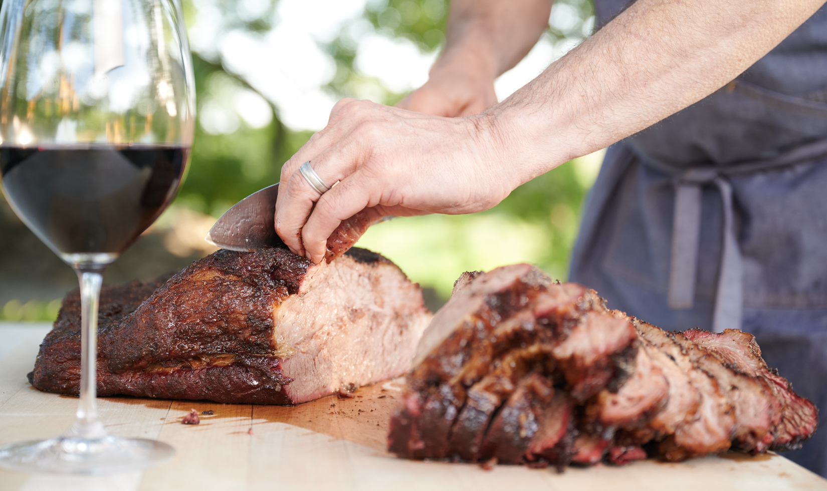 Food Pairing with Cabernet Sauvignon hands cutting brisket with knife and red wine glass on table