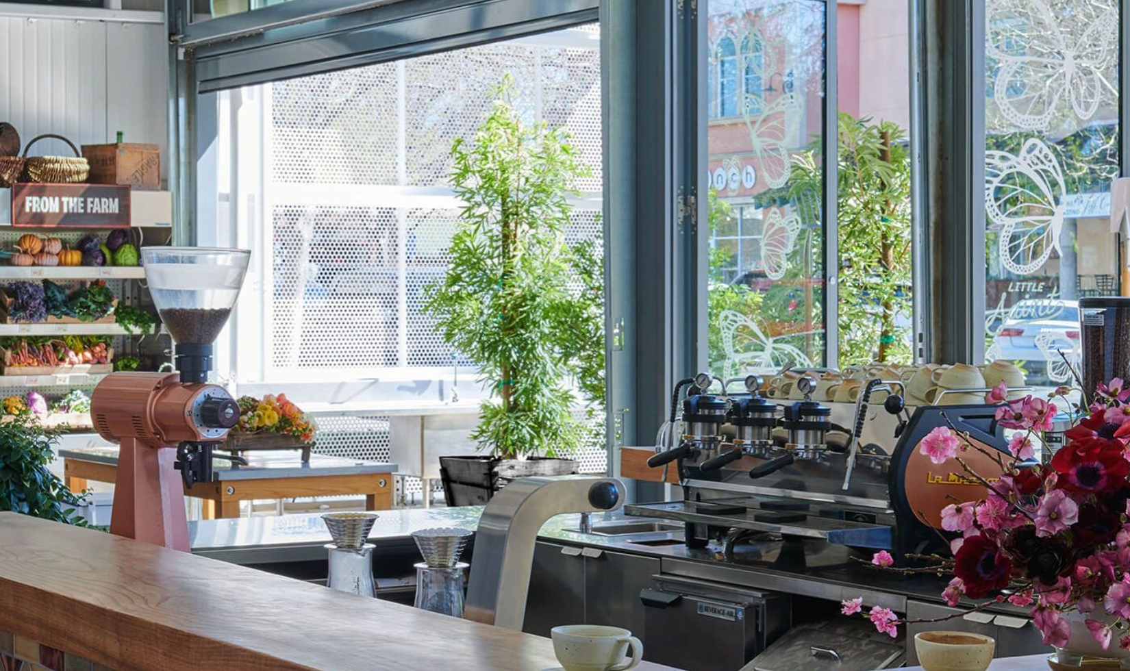 Counter in restaurant with Italian coffee machine in background with rows fresh lined with fresh produced off to the side