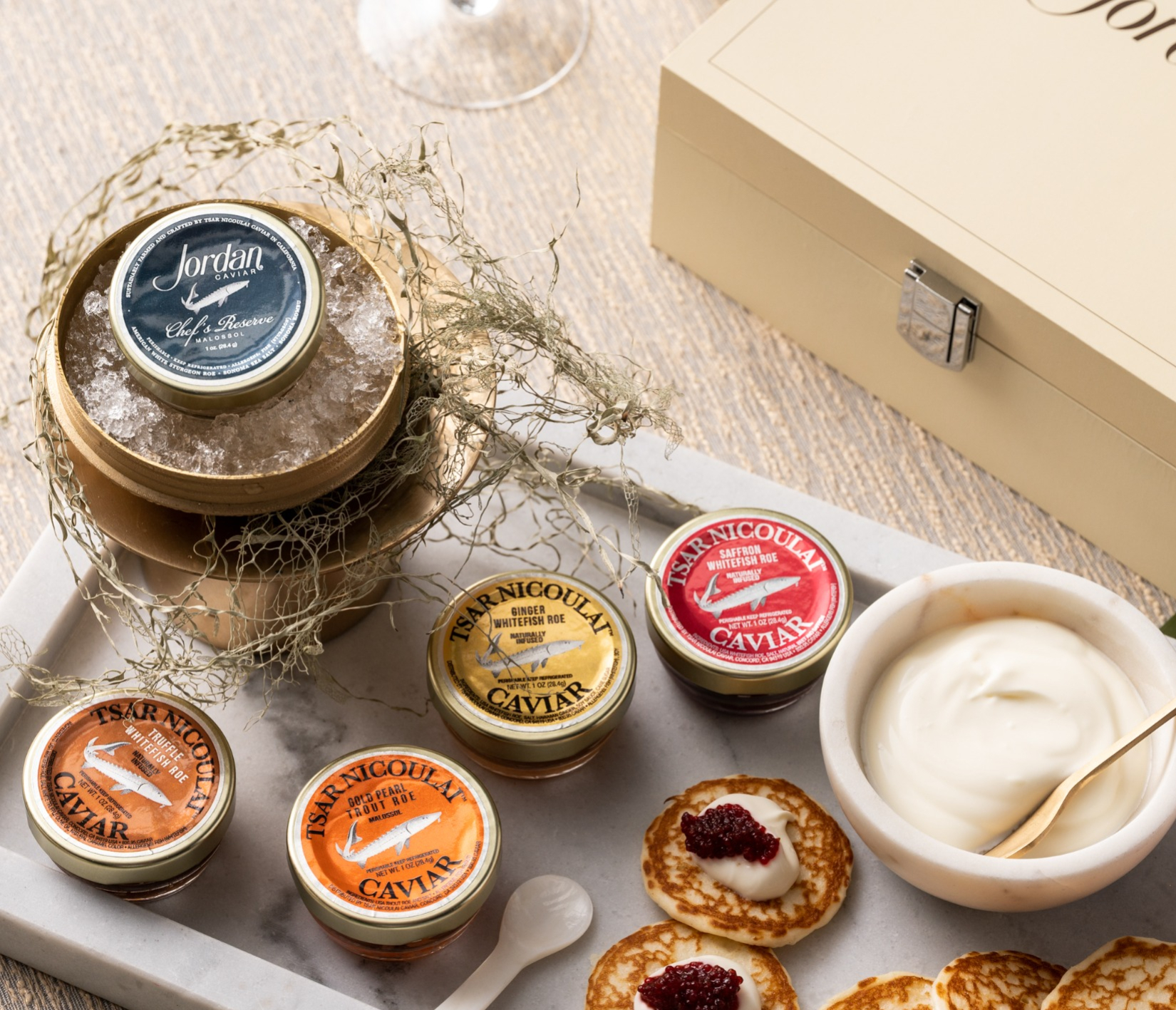 Dishes of caviar on marble tray with creme fraiche and blinis.