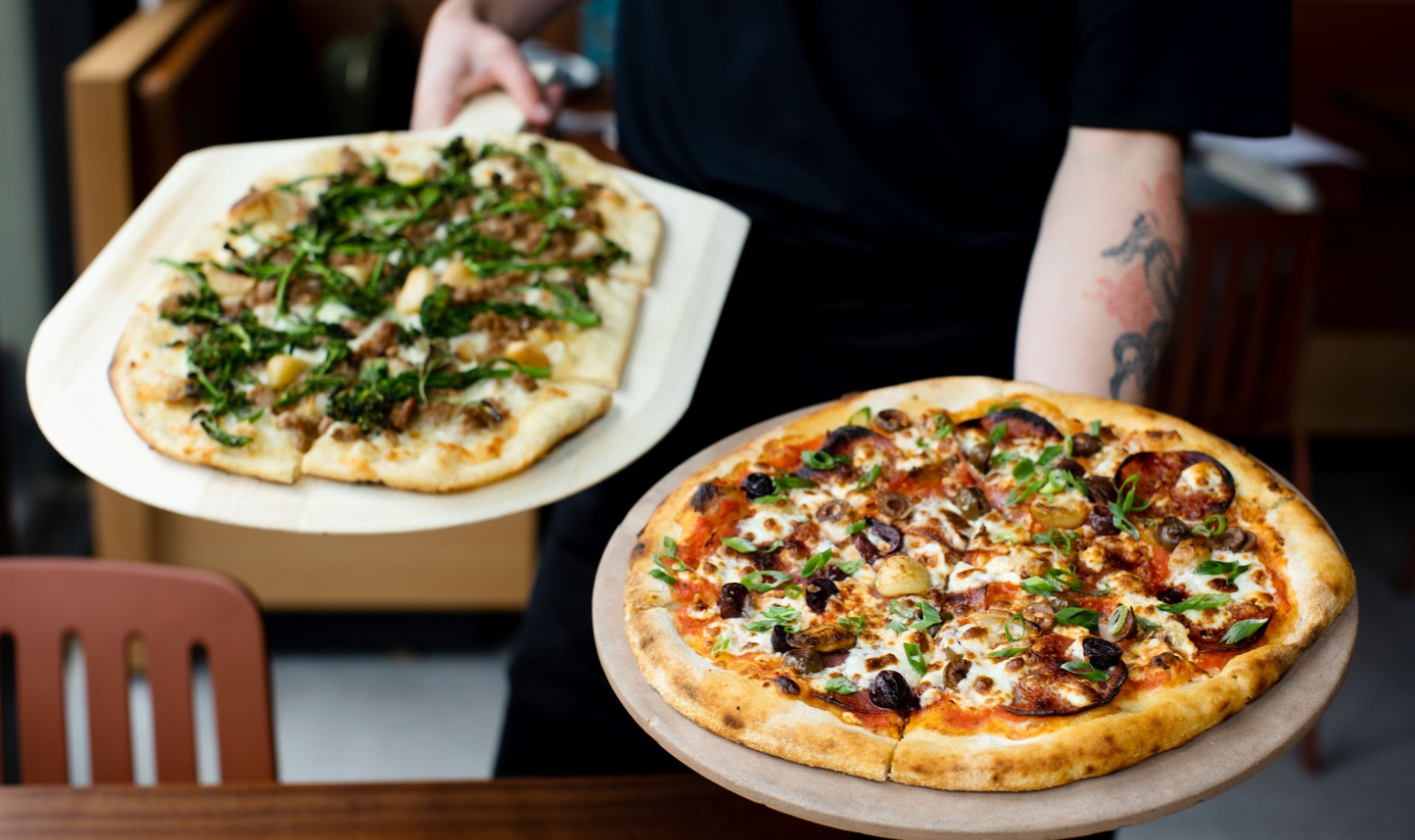 pizzas on pizza trays held by chef
