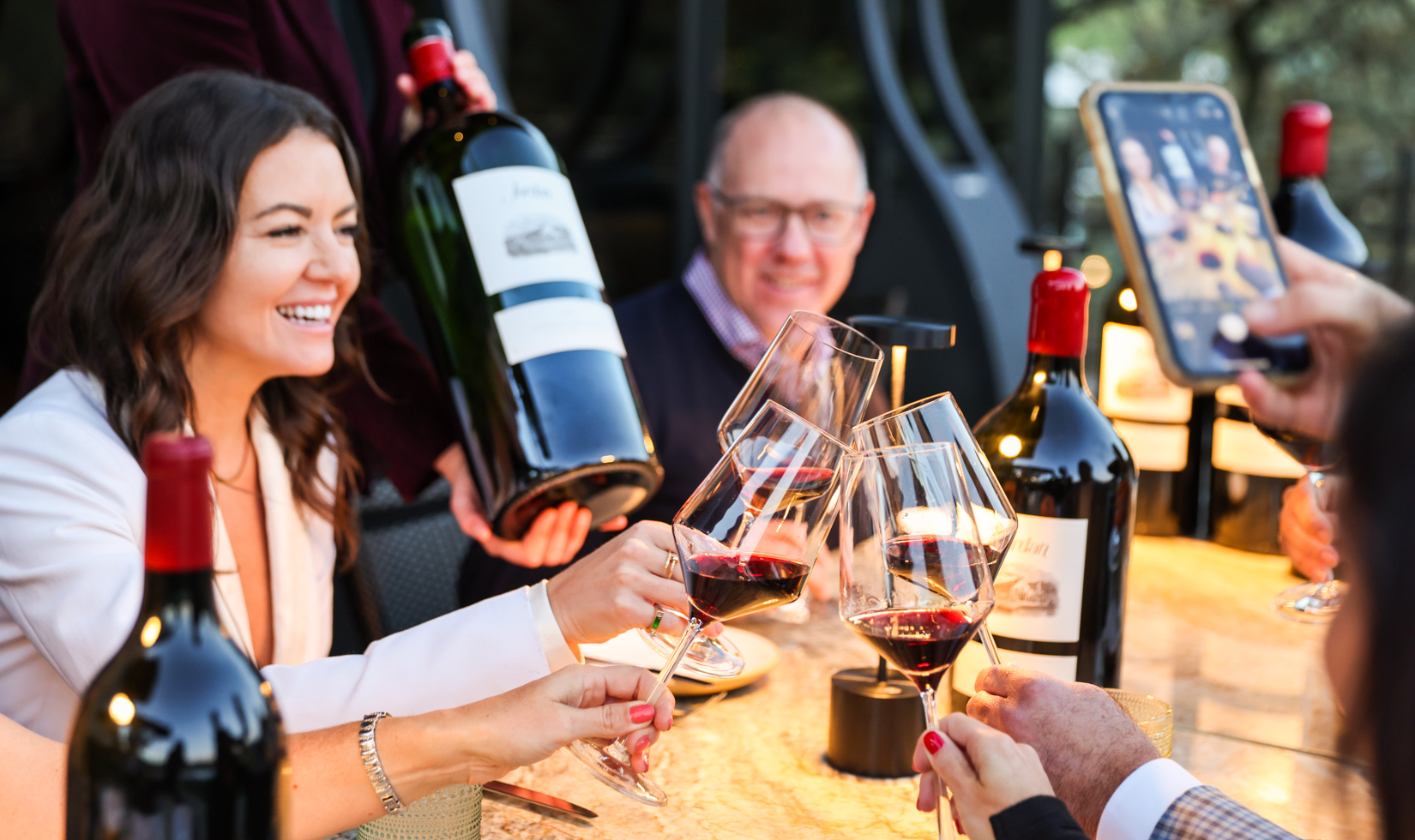 group of friends toasting with red wine around the dinner table
