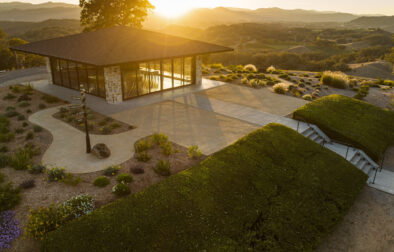 Modern glass building on hilltop overlooking vineyards