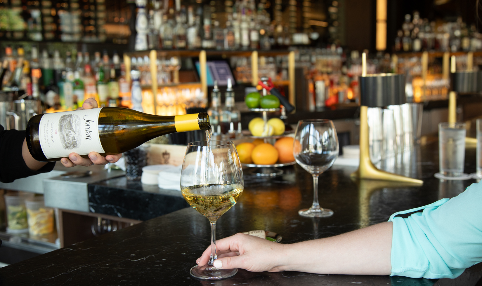 bottle of chardonnay pouring into a wine glass at a restaurant bar
