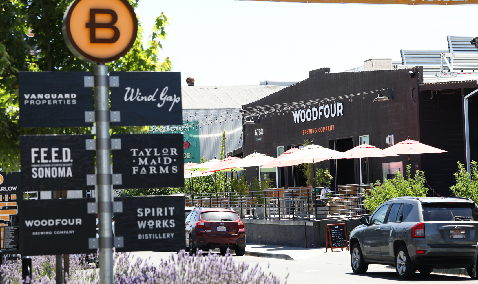 black street signs in outdoor market with cars lined on street 