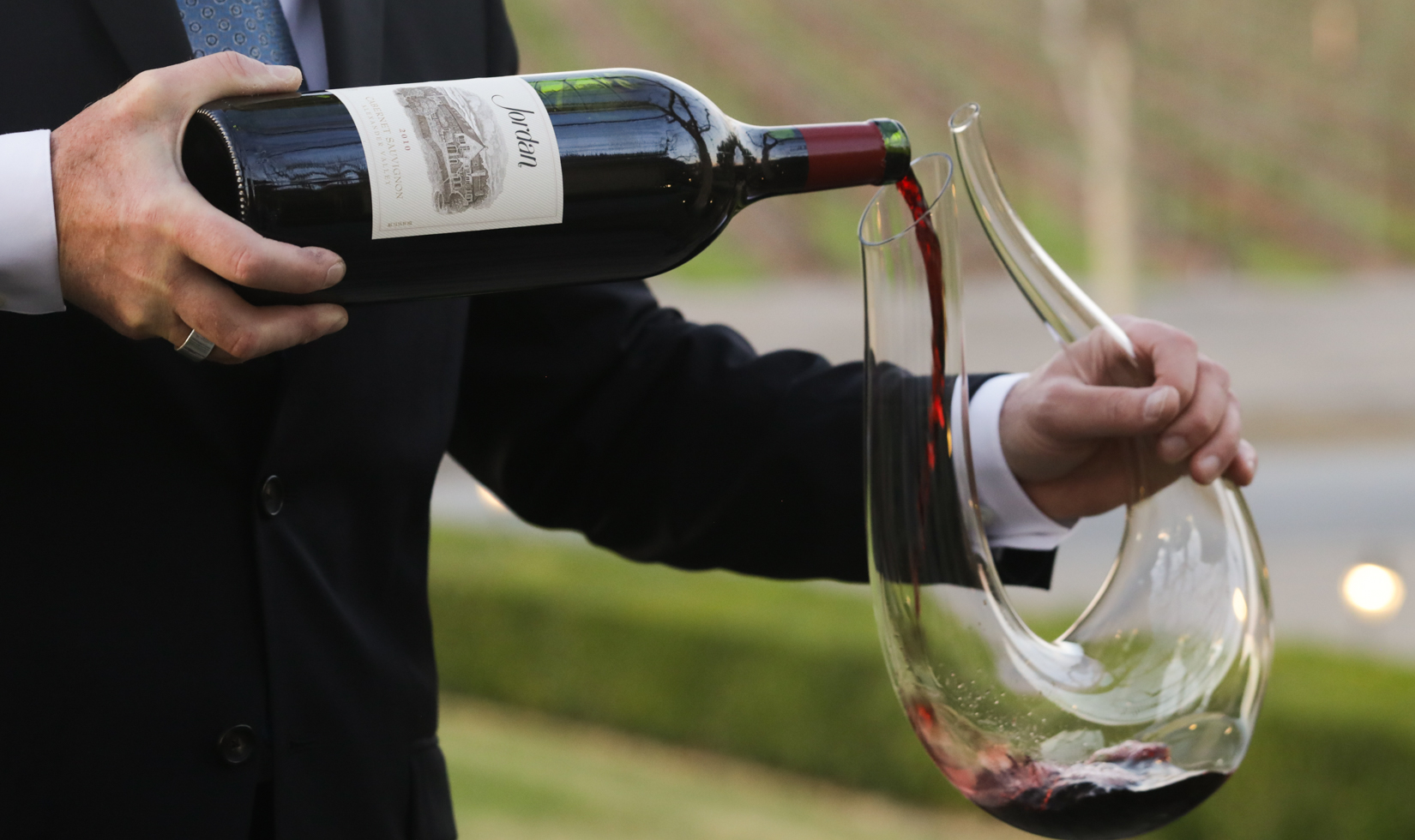 bottle of cabernet magnum pouring wine into glass decanter