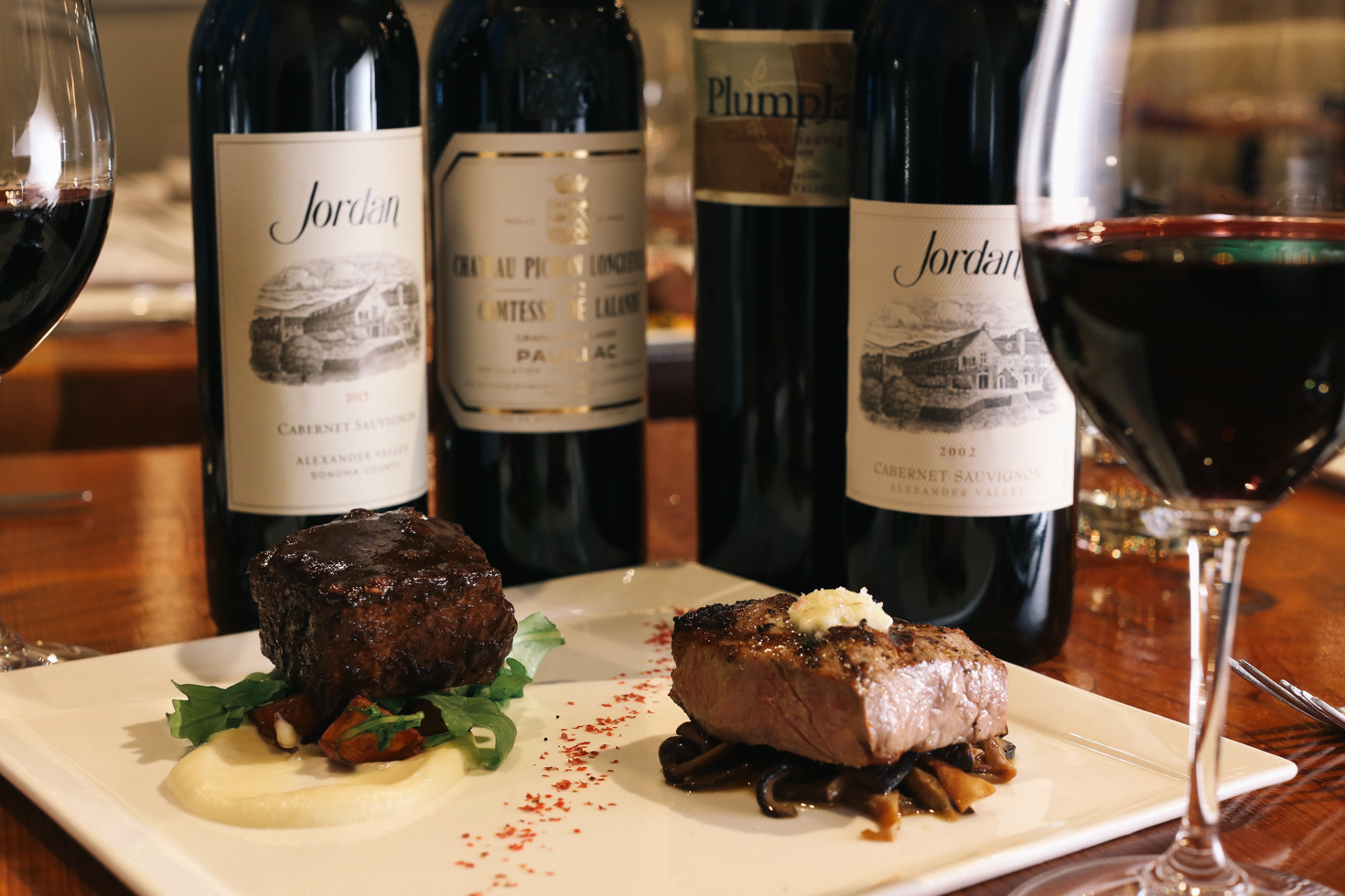 bottles of cabernet on restaurant table with cuts of steak