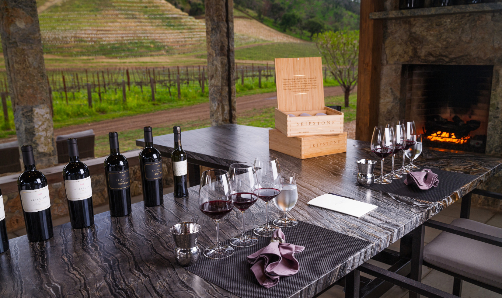 Table set for a wine tasting in front of fireplace with vineyard views