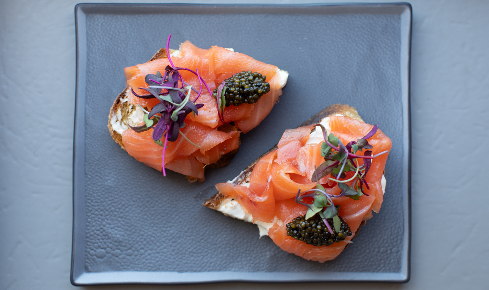 smoked salmon toast on charcoal plate with caviar