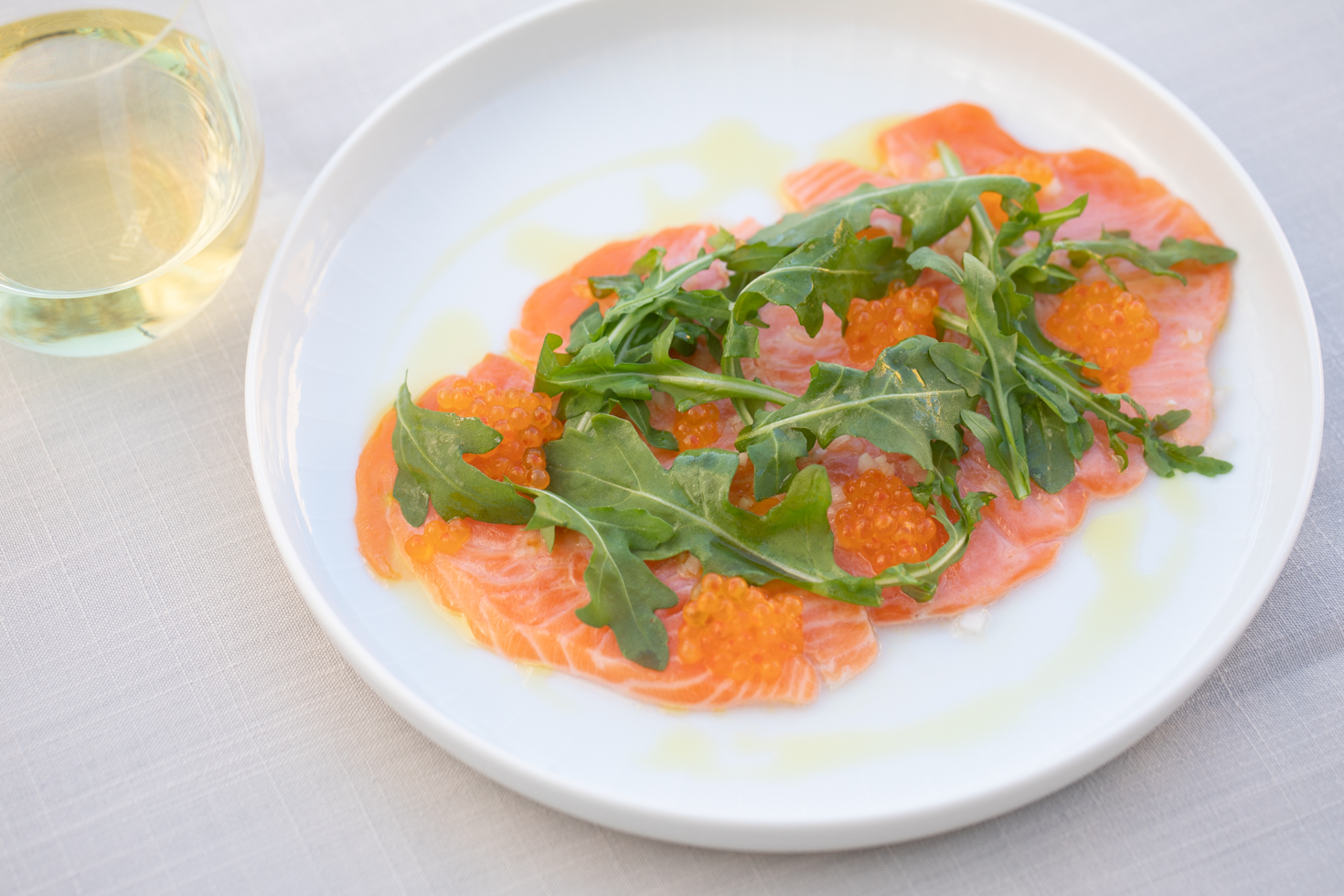 salmon paillard with arugula and chardonnay glass