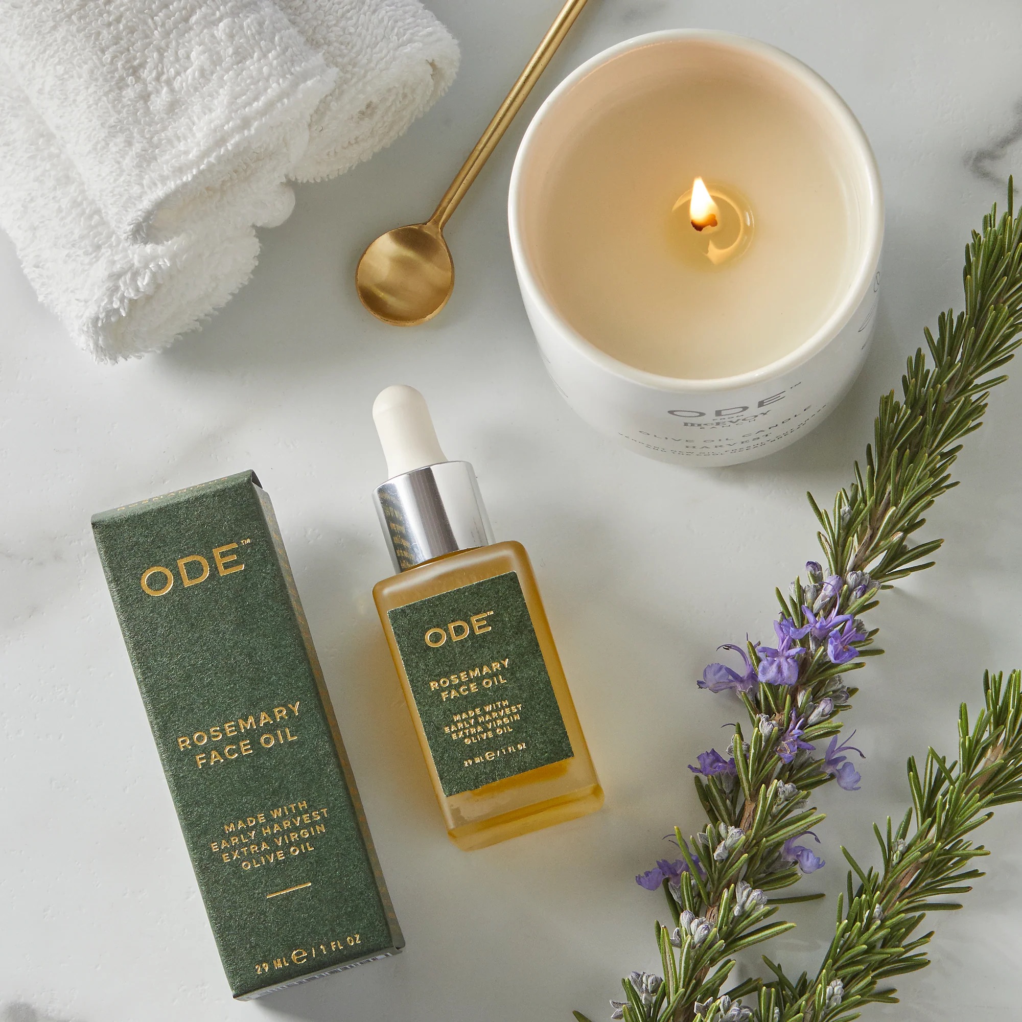 rosemary face oil with candle on marble surface