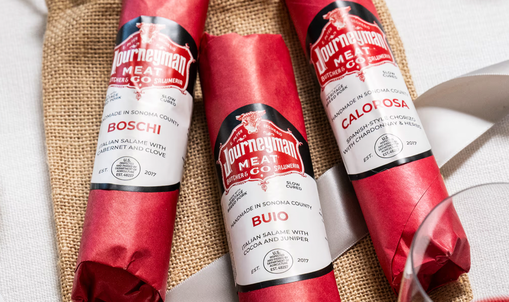 Three wrapped Journeyman Meat Co. salami varieties.