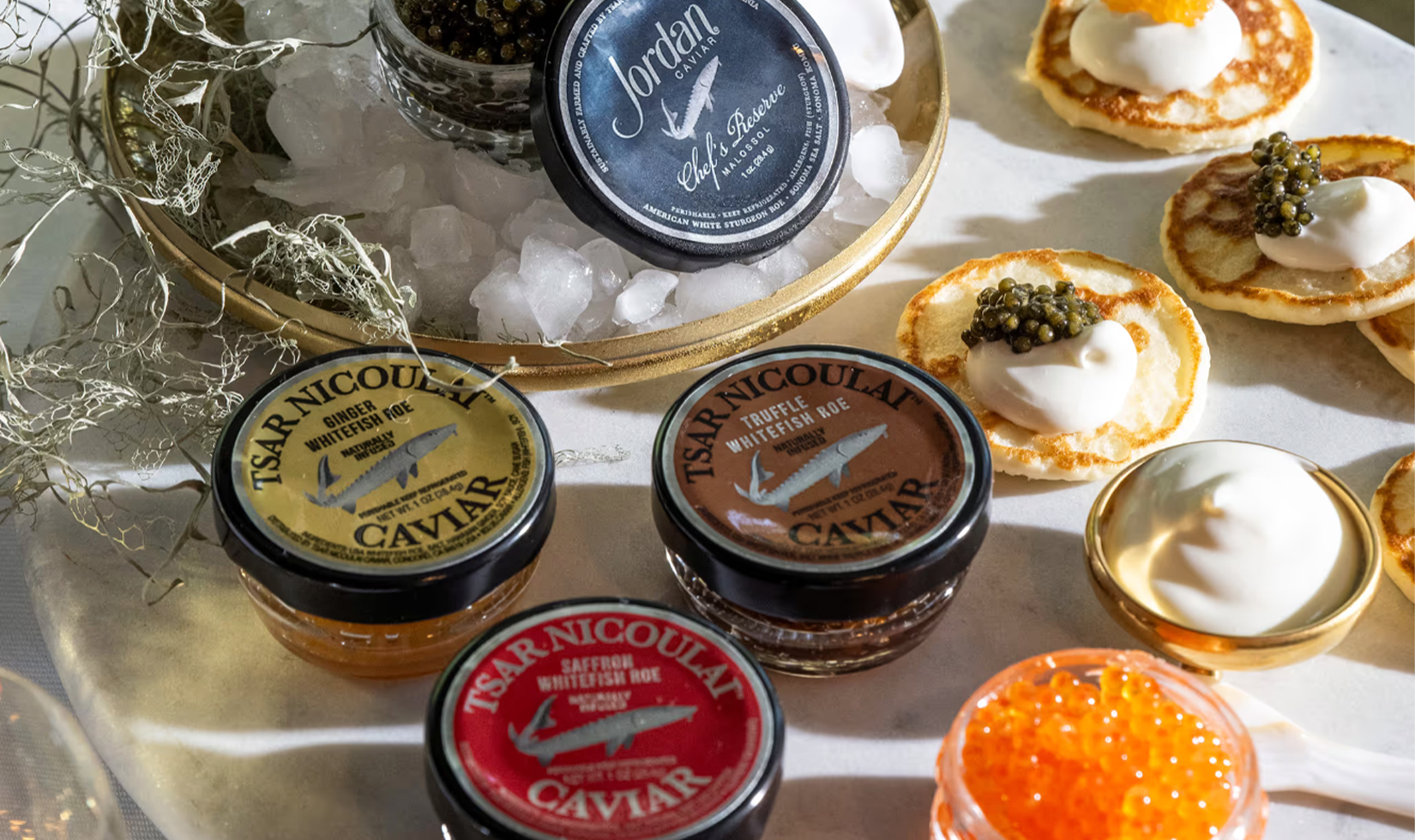 Assorted caviar jars and blinis with crème fraîche.